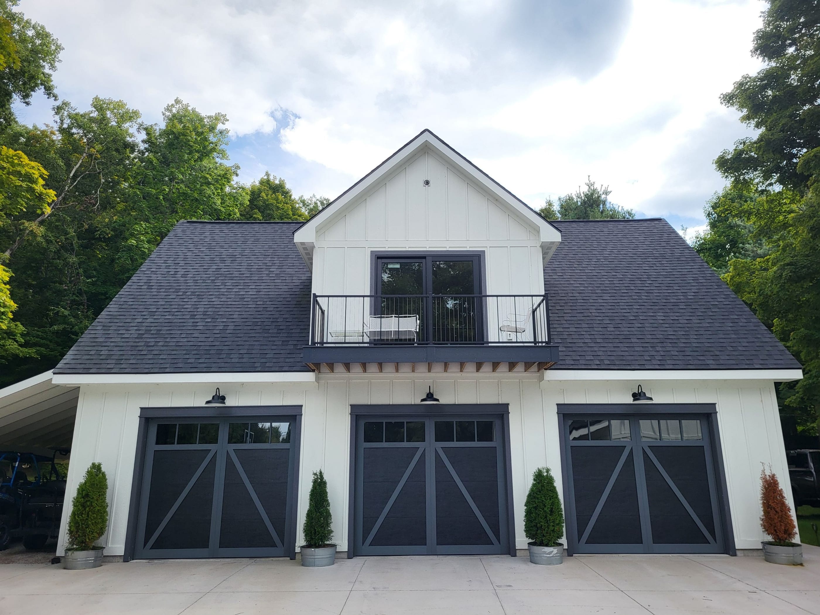 A white carriage house with three black Haas carriage doors installed by B&B
