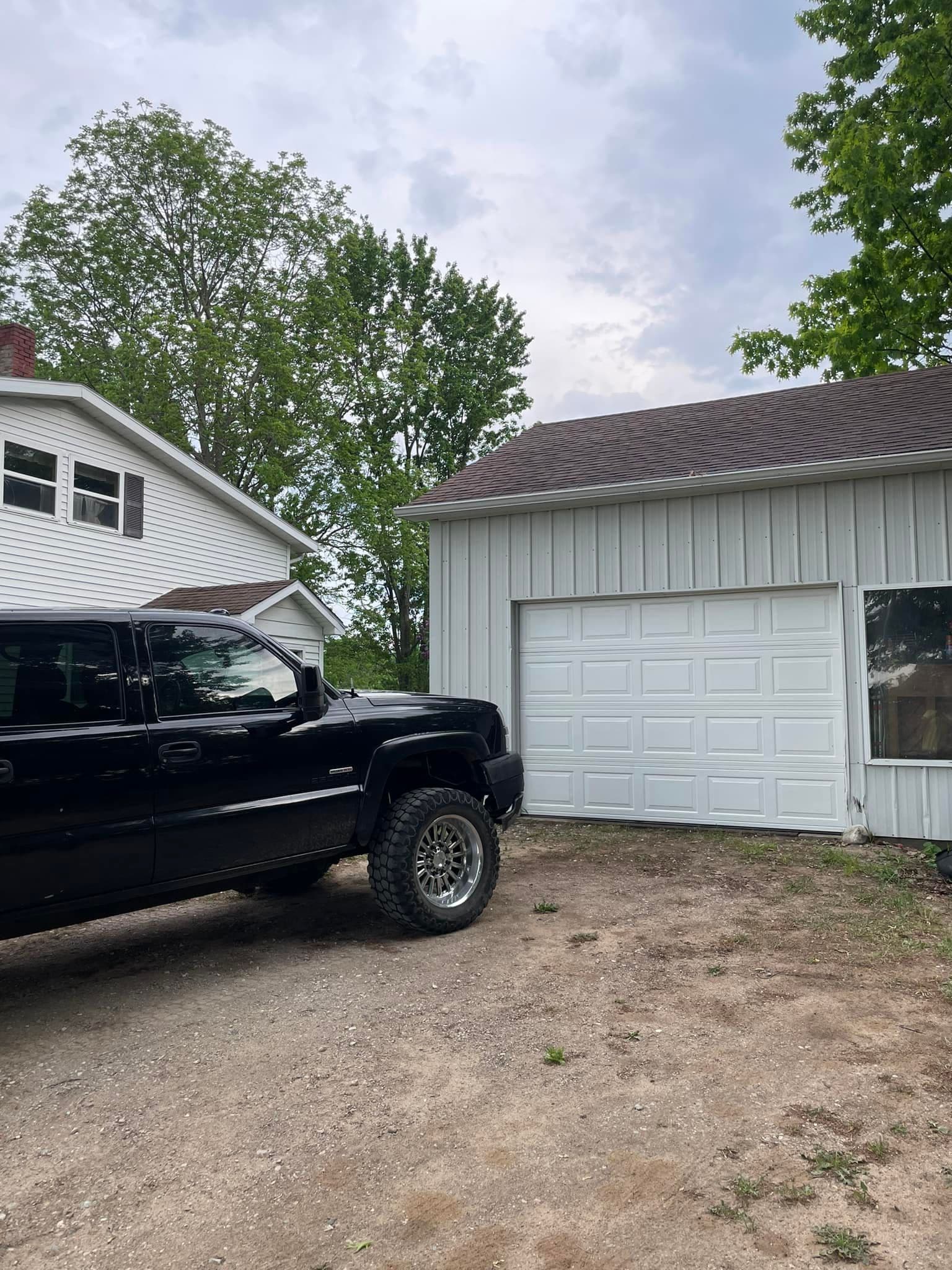 White garage door on a small outbuilding beside a pickup truck