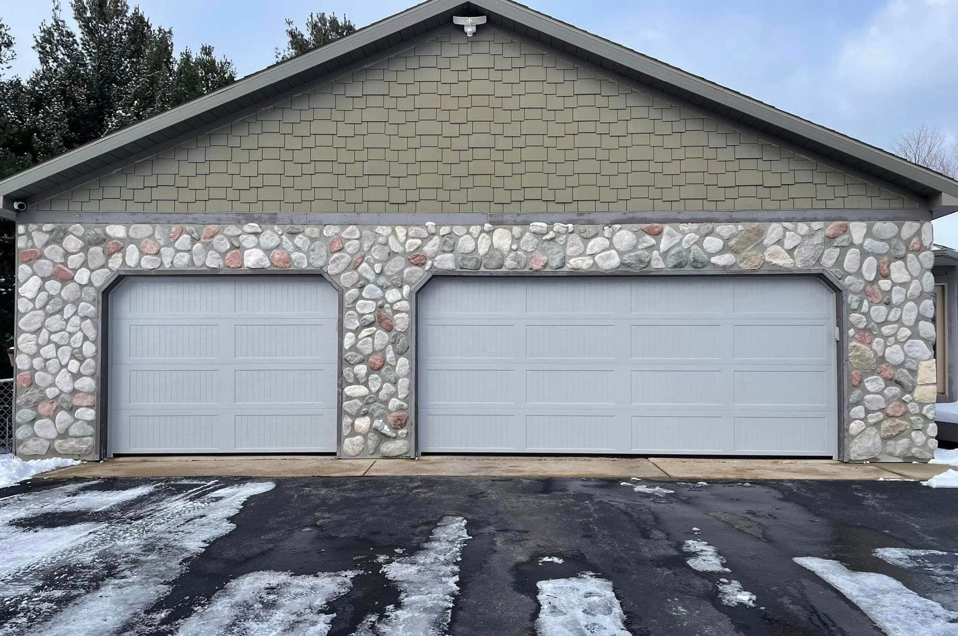 Two white raised-panel garage doors on a stone home