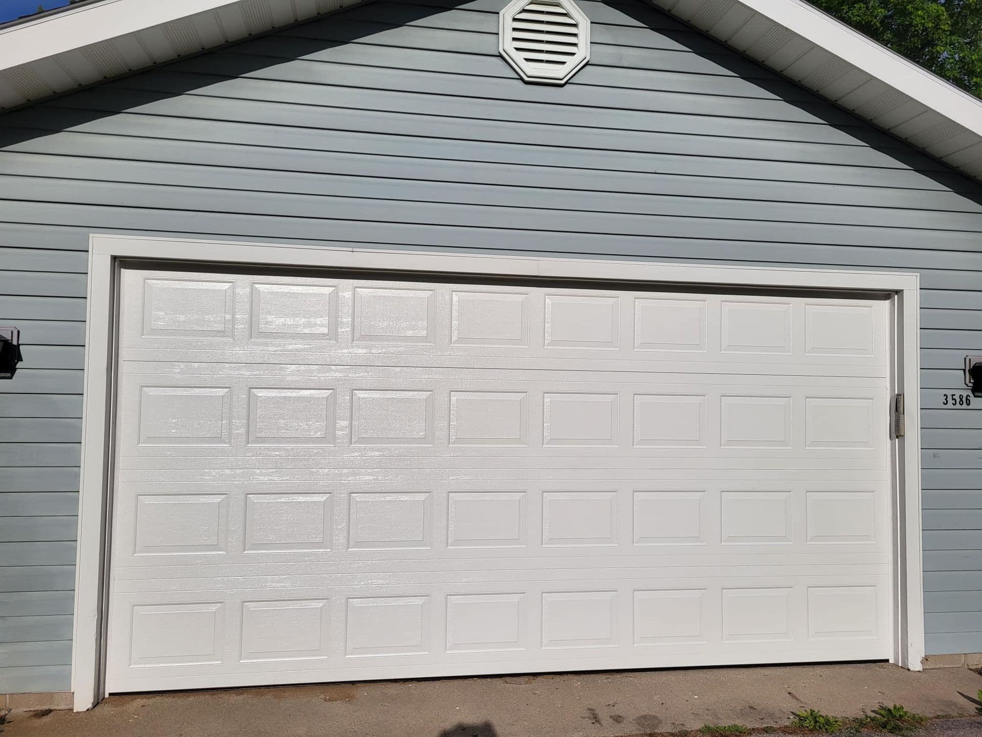 White raised-panel garage door closed tight to the driveway